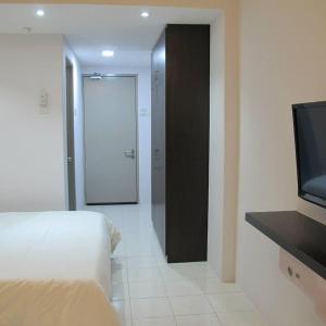 a bedroom with a bed and a door with a television at Pangkor Lot 10 Moonlight in Kampong Sungai Udang
