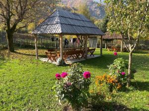 a gazebo with benches and flowers in a yard at Guest House Prebibaj in Curraj i Epërm