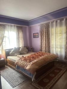 a bedroom with a bed with purple walls and windows at The Golden Attic in Yangang