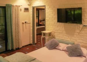 a living room with a tv on a brick wall at The Rising Sun Farm Karjat - Luxury Stays - Couple Friendly in Karjat