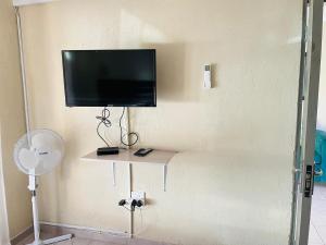 a flat screen tv on a wall with a fan at Druza’s guest house in Rustenburg