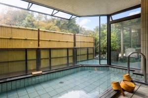 a swimming pool in a building with a large window at LiVEMAX RESORT Okudogo in Matsuyama