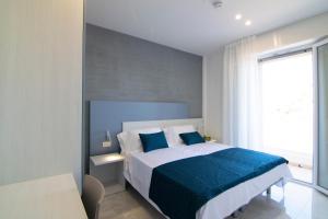 a bedroom with a white bed with blue sheets and a window at Residence Flow-R in Riccione +65 photos