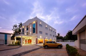 a yellow car parked in front of a white building at Hotel Maas Residency in Māvelikara