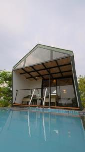 a swimming pool with a house with a glass extension at VerdEra Wild - Wilpattu in Wilpattu +33 photos