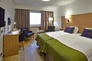 a hotel room with a large bed and a desk at Hotell Högland in Nässjö
