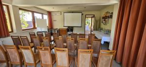 ein Konferenzraum mit Tisch, Stühlen und Bildschirm in der Unterkunft Hotel Villa Pax in Balatonalmádi