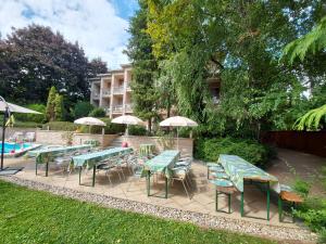 eine Gruppe von Tischen und Stühlen mit Sonnenschirmen in der Unterkunft Hotel Villa Pax in Balatonalmádi