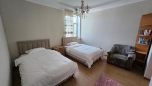 a bedroom with two beds and a chair and a chandelier at 华人民宿 in Almaty