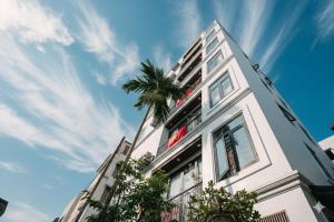 a tall white building with a palm tree at Chic & Stylist Studio Lakeview in Hanoi