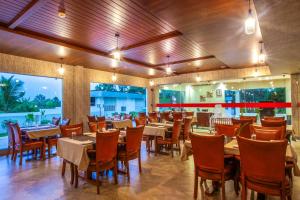 a restaurant with tables and chairs in a room at Hotel Maas Residency in Māvelikara