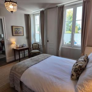 a bedroom with a bed and a chair and windows at Repos à Ribérac B&B in Ribérac