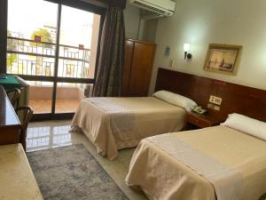 a hotel room with two beds and a window at St.Joseph Hotel in Luxor