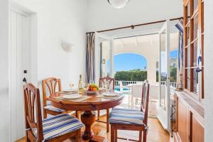 a dining room with a table and chairs and a balcony at Villa Caprice by Villa Plus in S'Algar