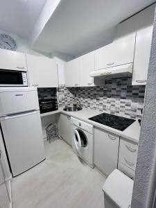 a kitchen with white cabinets and a washer and dryer at Laguna 88 in La Mata