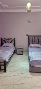 a bedroom with two beds and a lamp on the wall at Spacieux Appartement Selouane Nador in Selouane