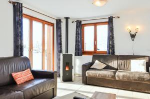 a living room with a leather couch and a television at FeWo im Chalet Schneeflöckli in La Tzoumaz