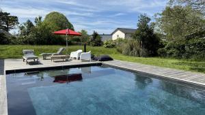 a swimming pool with two chairs and an umbrella at Villa Koad - piscine privee in Trébeurden