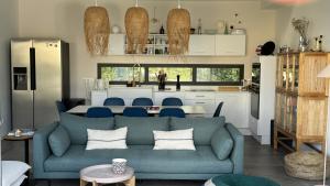 a living room with a blue couch and a kitchen at Villa Koad - piscine privee in Trébeurden