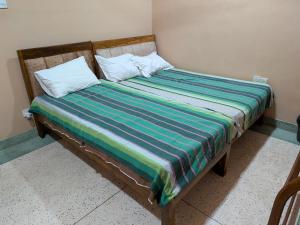 a bed with two pillows and a striped blanket at Seethevi Hotels in Batticaloa