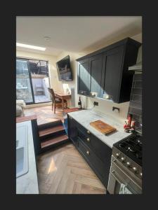 a kitchen with black cabinets and a dining room with a table at Spacious House In Guildford in Stoughton