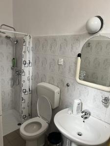 a white bathroom with a toilet and a sink at Green Door Hostel in Tirana