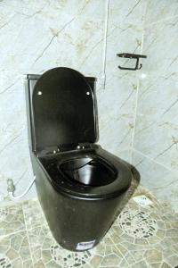 a black toilet with a black seat in a bathroom at Dawn Emeka Hotels in Akwa