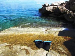 a pair of shoes sitting on a rock near the ocean at Holiday house Jakov in Gdinj