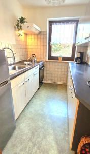 a kitchen with white cabinets and a sink and a window at Waitzdorfer Landhaus Pieper in Hohnstein