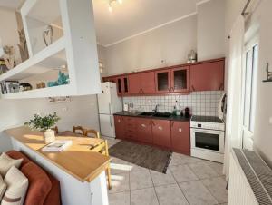 a kitchen with red cabinets and a wooden table at Mairi’s Apartment in Nea Artaki