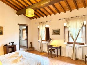 a bedroom with a bed and a desk and windows at Vitalenta Agriboutique in Pienza
