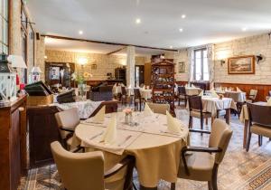 a dining room with tables and chairs in a restaurant at LOGIS Hôtel & Restaurant - Au Bord du Lac in Saint-Rémy-lès-Chevreuse