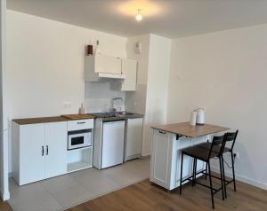 a small kitchen with white cabinets and a table at Cocon Seine parisii in Sartrouville +7 photos