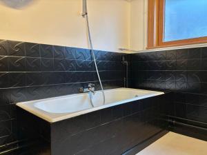 a bath tub in a bathroom with black tiles at Villa Bonheur in Koksijde +22 photos