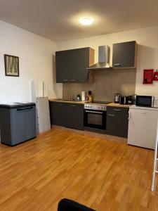 a kitchen with black and white appliances and wooden floors at Linz Wasserwald - cozy 2BR Apartment in Linz +13 photos