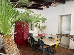 a table and chairs in a room with palm trees at Baglio Cusenza Rooms in San Vito lo Capo