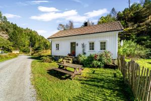 a small white house with a picnic table in front of it at Det Hvite Hus - Fosseland Hytter in Feda +6 photos
