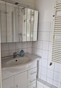 ein weißes Badezimmer mit Waschbecken und Spiegel in der Unterkunft ZWEITE REIHE FLAIR Ferienwohnungen in Krakow am See + 21 Fotos