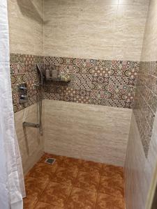 a bathroom with a shower with a tiled wall at Bhoomi in Mysore +3 photos