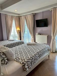 a bedroom with a bed and a tv and windows at Maison Dang Boutique Hotel in Chiang Mai