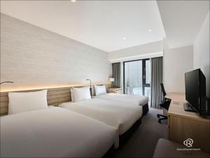 a hotel room with two beds and a television at Daiwa Roynet Hotel Sendai Ichibancho PREMIER in Sendai