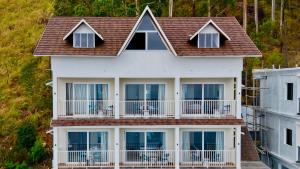 a white house with balconies and a roof at Clouds end Resorts Munnar in Jāmb