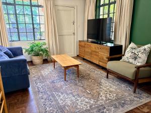 a living room with a tv and a couch and a table at Oatlands Cottages in Grahamstown