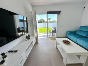 a living room with a blue couch and a tv at Chalet Chiclana in Chiclana de la Frontera