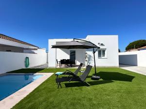 a patio with two chairs and an umbrella next to a pool at Chalet Chiclana in Chiclana de la Frontera