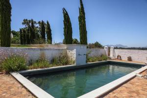 a pool in a backyard with trees and a fence at Hawksmoor House in Stellenbosch