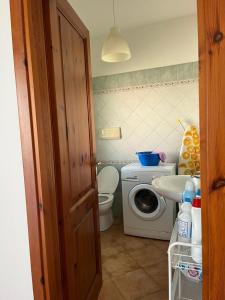 a small bathroom with a washing machine and a sink at Casa FLORE in Orosei