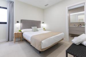 a white bedroom with a large bed and a bathroom at Brisamar Suites I by VillaGranCanaria in Arinaga