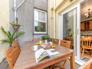 a wooden table on a patio with a book at 6 Bed in Tenby oc-fb220 in Tenby