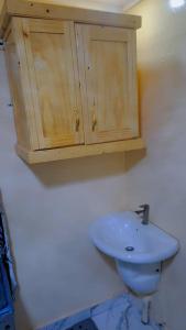a bathroom with a sink and a wooden cabinet at Secka Apartment in Sukuta